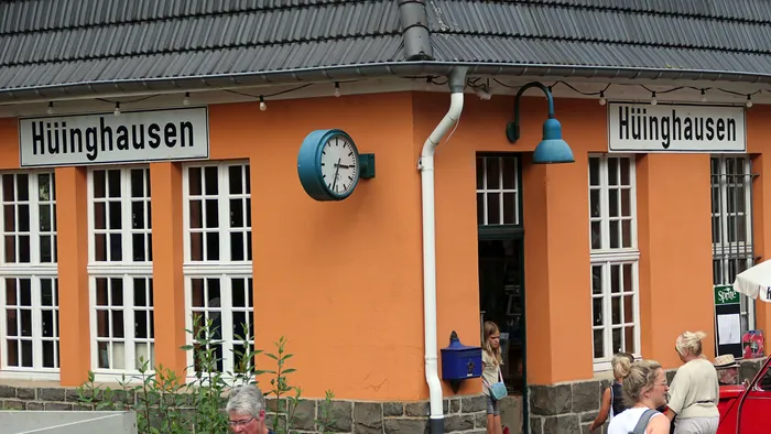 Der Bahnhof Hüinghausen mit dem Schriftzug über dem Eingang und einer großen Bahnhofsuhr.