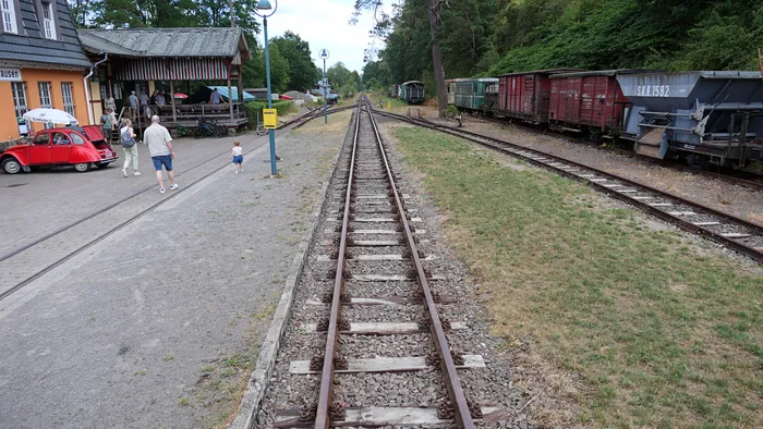 Blick auf Gleise und Waggons der Sauerländer Kleinbahn vor dem Bahnhof, während Besucher den Fahrtag erkunden.