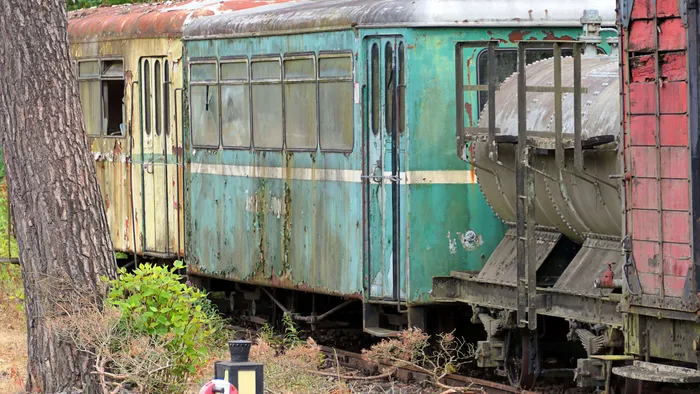 Ausgemusterte Waggons der Sauerländer Kleinbahn stehen auf einem Gleis, teilweise mit Rost und abblätternder Farbe.