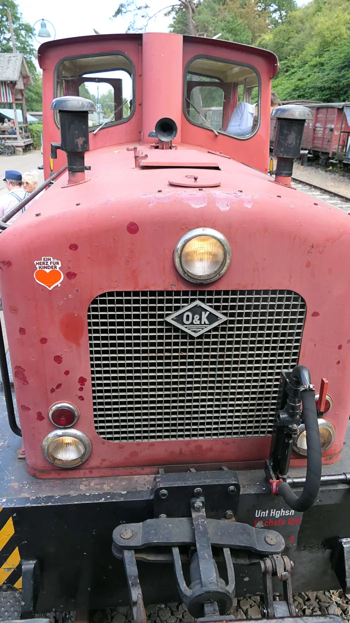 Roter Schienenfahrzeug mit Kühlergrill und Scheinwerfern, beschriftet mit „O&K“.