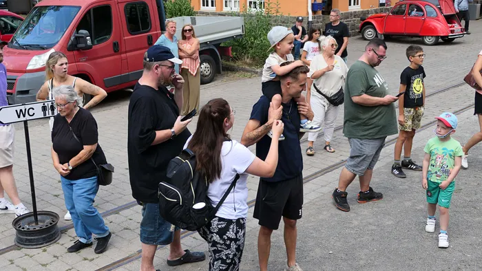 Menschen stehen und fotografieren auf Gleisen vor einer roten Sauerländer Kleinbahn.