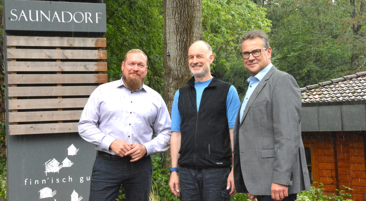 Ricardo Rietschel, Michael Krüger und Volker Neumann stehen vor dem Schild des Saunadorfs.