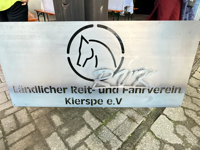 Schild des Ländlichen Reit- und Fahrvereins Kierspe mit stilisierter Pferdekopf-Umrandung und dem Schriftzug „Ländlicher Reit- und Fahrverein Kierspe e.V.“ zur Feier des 100-jährigen Jubiläums.
