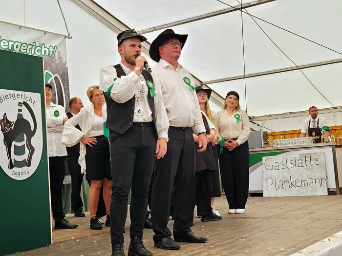 Mitglieder der Biergerichtskommission des Schützenvereins Eiringhausen stehen auf einer Bühne im Festzelt, während ein Mann in ein Mikrofon spricht.