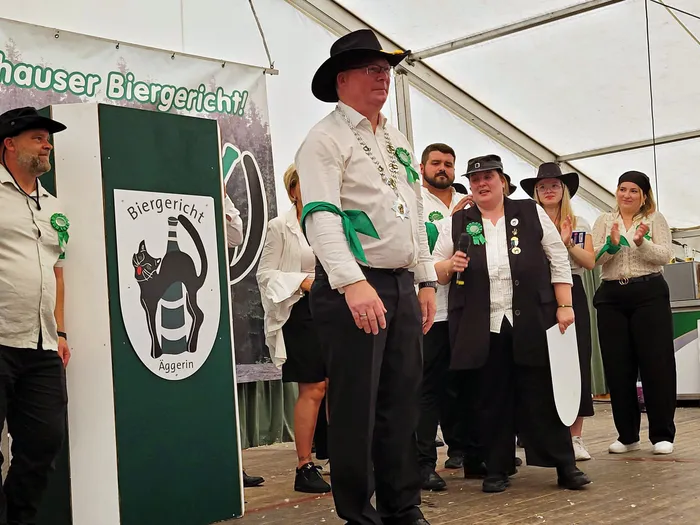 Mitglieder der Biergerichtskommission des Schützenvereins Eiringhausen stehen auf einer Bühne in einem Festzelt, eine Frau spricht in ein Mikrofon.