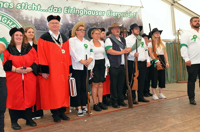Die Biergerichtskommission des Schützenvereins Eiringhausen in Kostümen, teils in roten Roben, teils in weißen Hemden, steht in einem Festzelt.