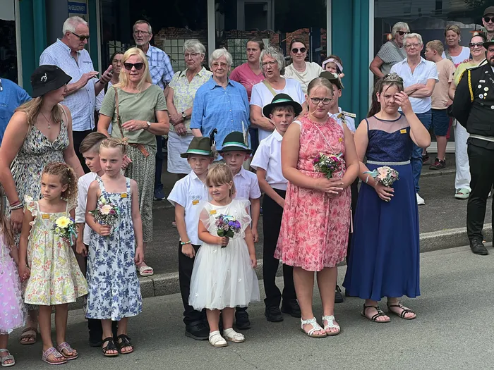 Kinder und Jugendliche in festlicher Kleidung mit Blumensträußen stehen beim Schützenfest-Festumzug in Eiringhausen.