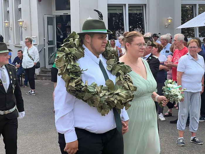 Ein Mann mit einem großen Blattkranz und eine Frau in einem hellgrünen Kleid beim Festumzug des Schützenfests in Eiringhausen.