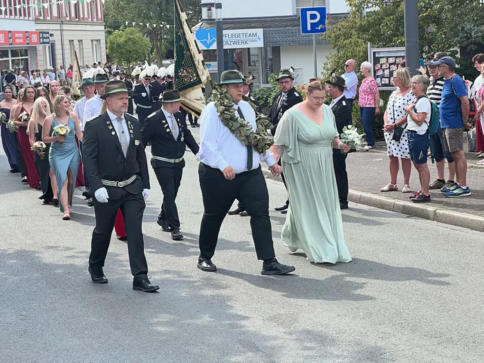 Teilnehmer des Schützenfest-Festzugs in Eiringhausen ziehen in Uniformen und festlicher Kleidung durch die Straße.