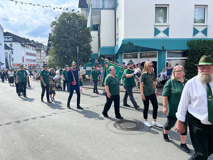 Teilnehmer in grünen Hemden und Uniformen ziehen mit einer Fahne durch die Straßen von Eiringhausen.