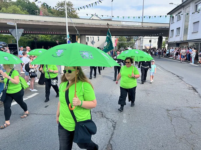 Teilnehmer in leuchtend grünen T-Shirts und mit grünen Schirmen ziehen bei einem Festumzug durch eine Straße in Eiringhausen.