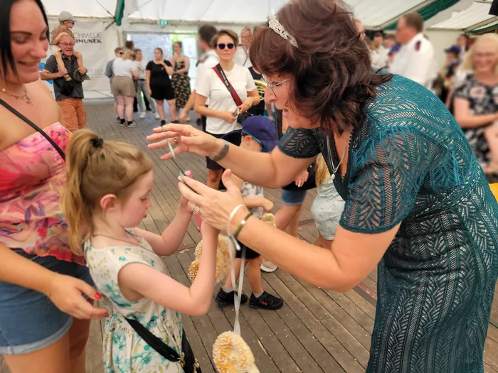 Eine Frau in einem blaugrünen Kleid und ein kleines Mädchen halten gemeinsam einen dekorativen Gegenstand beim Kids Day des Schützenfests Eiringhausen.