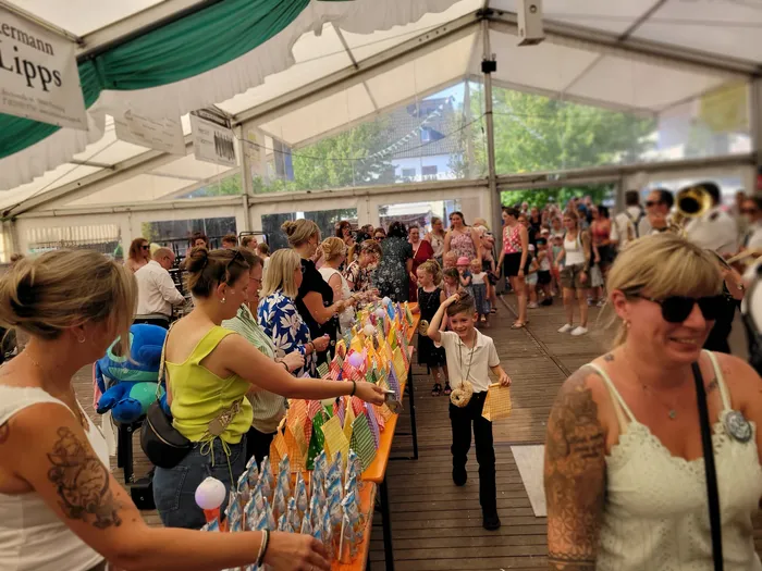 Menschenmengen unter einem Festzelt beim Kids Day des Schützenfests in Eiringhausen, mit einem Tisch voller bunter Geschenktüten und einem Jungen.