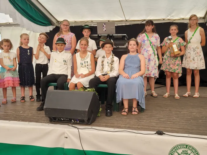 Eine Gruppe von Kindern und Jugendlichen auf einer Bühne beim Schützenfest Eiringhausen, einige in weißen Hemden und Hüten, ein Mädchen hält eine Trophäe.