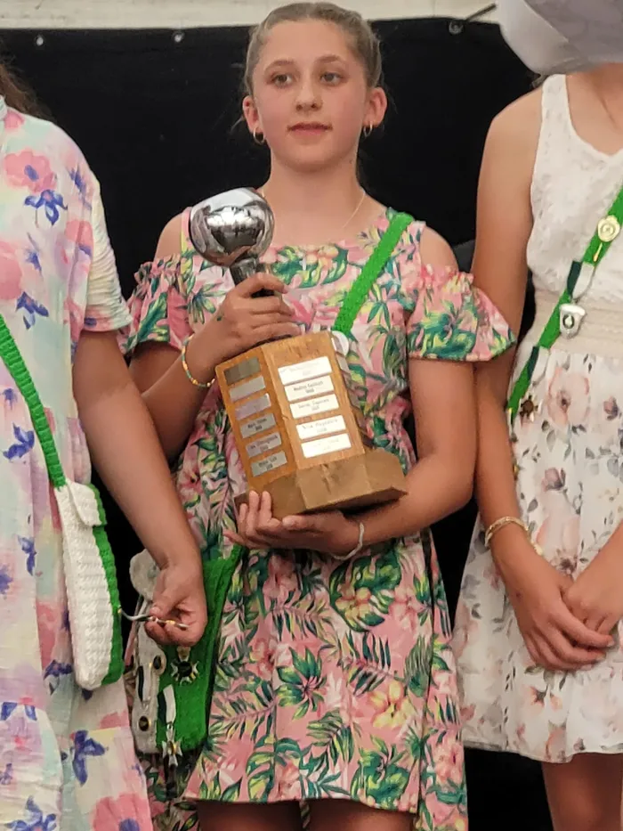 Ein Mädchen in einem rosa geblümten Kleid hält eine Holztrophäe mit einer silbernen Kugel beim Schützenfest in Eiringhausen.