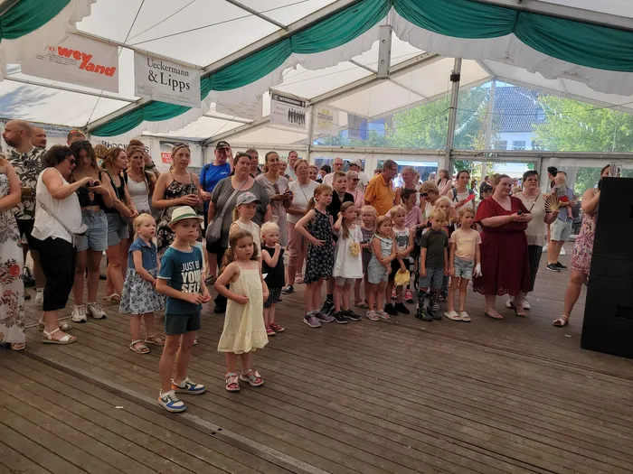 Eine Gruppe von Kindern und Erwachsenen steht auf einer Holzplattform unter einem Festzelt beim Schützenfest Eiringhausen.