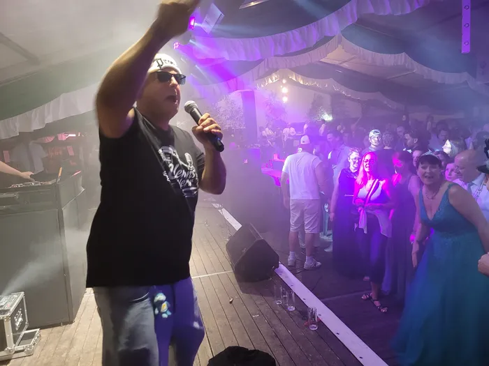 Clemens Werner singt mit erhobenem Arm in ein Mikrofon auf einer Bühne in einem Festzelt vor Publikum.