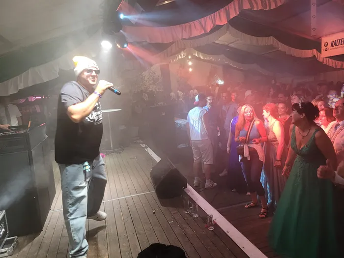 Clemens Werner singt mit einem Mikrofon in einem Festzelt vor einer Menschenmenge.