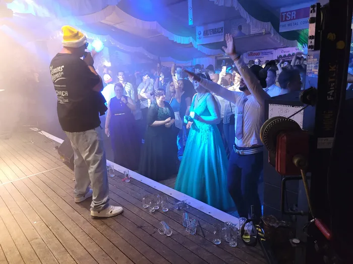 Clemens Werner steht auf einer Bühne in einem Festzelt vor einer Menschenmenge unter blauem Licht.