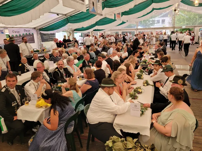 Viele Gäste sitzen an weiß gedeckten Tischen in einem großen Festzelt während des Krönungsabends des Schützenvereins Eiringhausen.