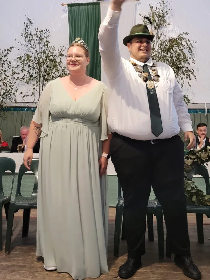 Alexandra Langenberg-Kasel in einem hellgrünen Kleid mit Diadem und Sascha Kasel mit einer zeremoniellen Königskette, grünem Hut und Krawatte.