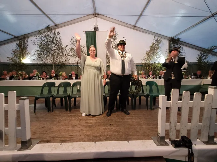 Sascha Kasel und Alexandra Langenberg-Kasel winken beim Krönungsabend des Schützenvereins Eiringhausen. Er trägt eine Königskette und sie ein Diadem.