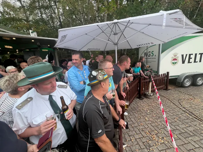 Menschenmenge beim Schützenfest in Eiringhausen unter einem großen weißen Sonnenschirm, im Vordergrund ein Mann in weißem Hemd und grünem Hut.