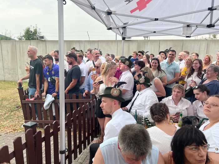 Eine Menschenmenge unter einem weißen Festzelt bei einem Schützenfest, einige Personen tragen traditionelle Hüte mit Federn.