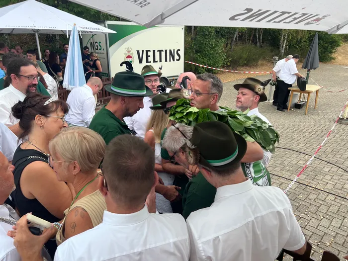 Sascha Kasel trägt einen großen grünen Kranz als neuer Schützenkönig bei einem Schützenfest in Eiringhausen.