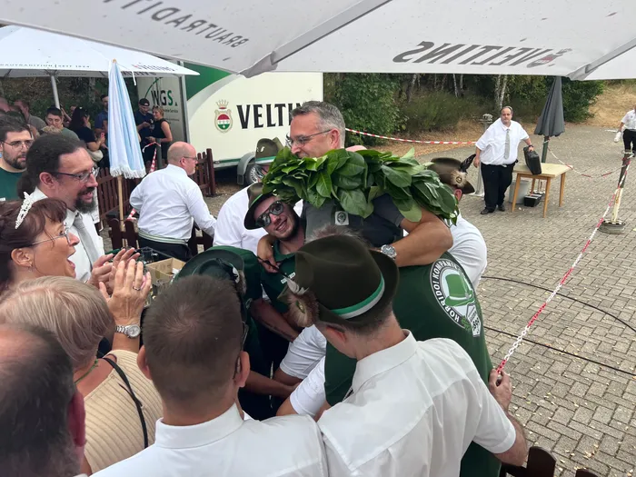 Eine Gruppe von Menschen in weißer Kleidung und grünen Hüten feiert den neuen Schützenkönig Sascha Kasel beim Schützenfest in Eiringhausen.