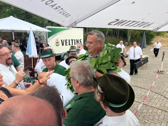 Sascha Kasel trägt einen großen Kranz aus grünen Blättern beim Schützenfest in Eiringhausen.