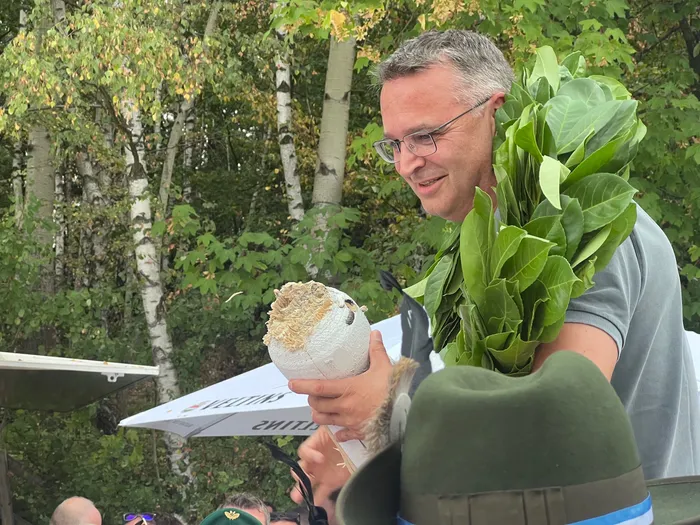 Sascha Kasel hält den geschossenen Königsvogel und trägt eine Girlande aus grünen Blättern.