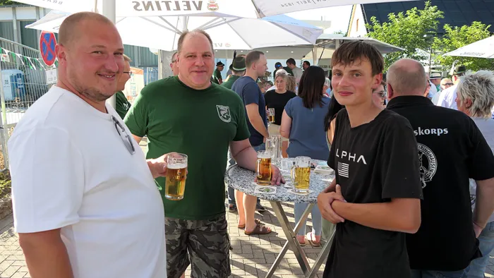 Männer der Kompanie Ohle stehen bei einem Schützenfest-Warm-up im Freien an einem Stehtisch mit Biergläsern.