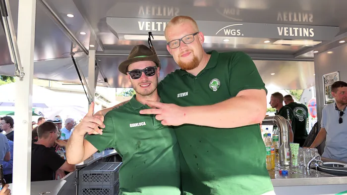 Zwei Männer in grünen Poloshirts mit den Namen Gianluca und Steven posieren gemeinsam an einem Stand beim Schützenfest-Warm-up.