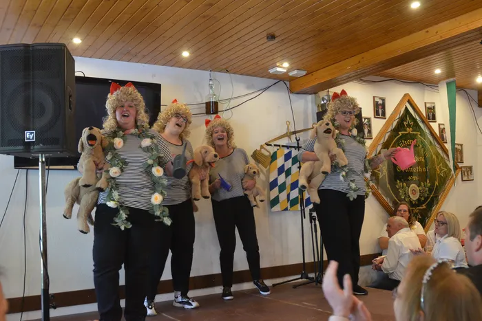 Fünf Personen mit blonden Perücken und gestreiften Oberteilen führen auf einer Bühne eine Puppenspiel-Performance auf.