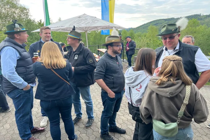 Eine Gruppe von Menschen in traditioneller Tracht steht und unterhält sich vor einem Zelt mit dem Schriftzug „Schützenverein Grünetal“. Im Hintergrund eine bewaldete Hügellandschaft.
