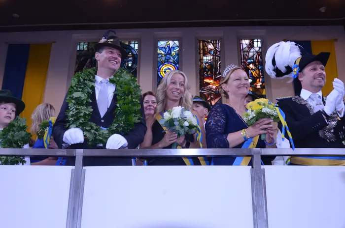Menschen auf einem Balkon während des Schützenfestes der Plettenberger Schützengesellschaft, mit Blumen und traditioneller Kleidung.