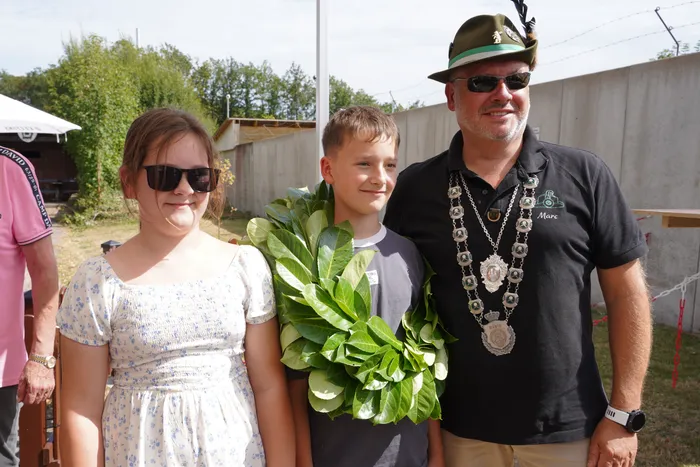 Kinderkönig Christian Schneider mit einem großen grünen Blattkranz, Königin Kiana Kotyczka und Schützenkönig Marc Stahlschmidt mit einer silbernen Schützenkette.