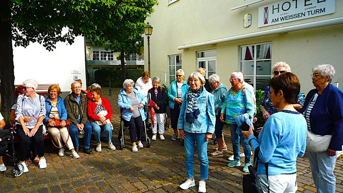 Eine Gruppe von Senioren steht und sitzt vor dem Hotel am Weissen Turm.