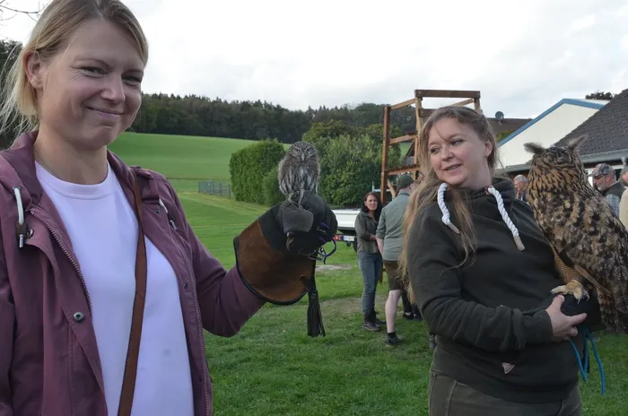 Zwei Frauen halten eine kleine und eine große Eule auf behandschuhten Händen bei einem Sommerfest.