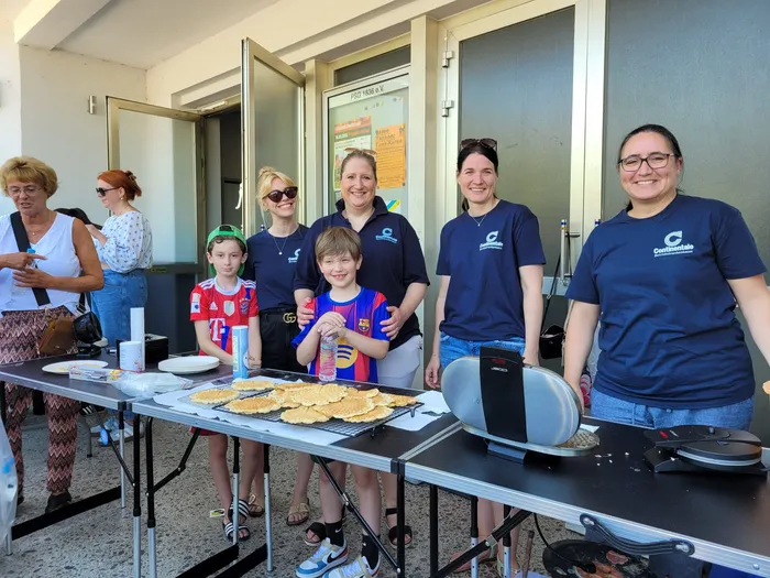Mitarbeiter des Vespa-Clubs Plettenberg verteilen Crêpes an einer Spendenaktion für krebskranke Kinder. Mehrere Personen stehen hinter einem Tisch mit Speisen und Getränken, während zwei Kinder Crêpes auswählen.