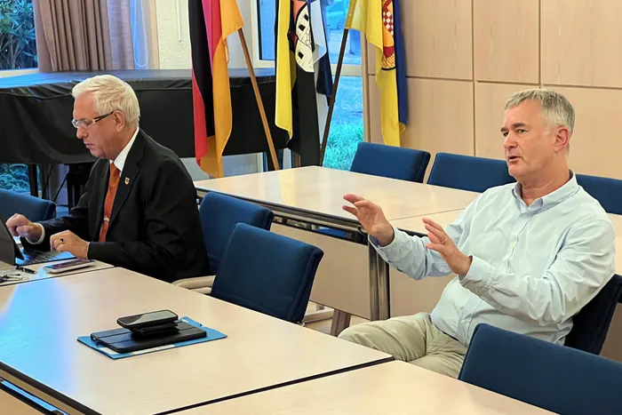 Dr. Uwe Allmann gestikuliert beim Sprechen, während Bürgermeister Ralf Beßler am Laptop arbeitet.