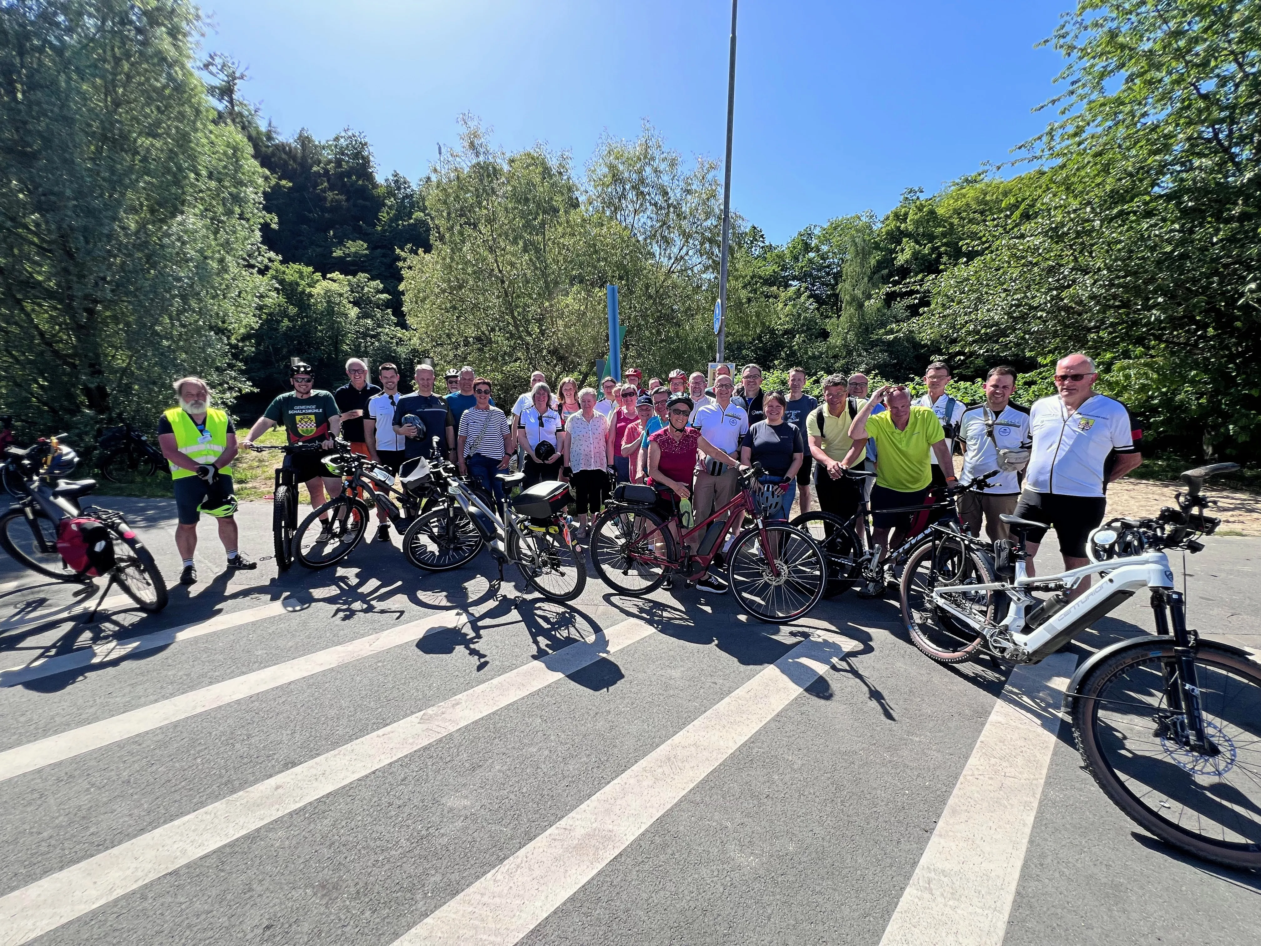 Eine große Gruppe Radfahrer steht mit ihren Fahrrädern auf einer Straße vor einer Baumkulisse. Sie nehmen am Auftakt des STADTRADELN 2026 in Werdohl teil.