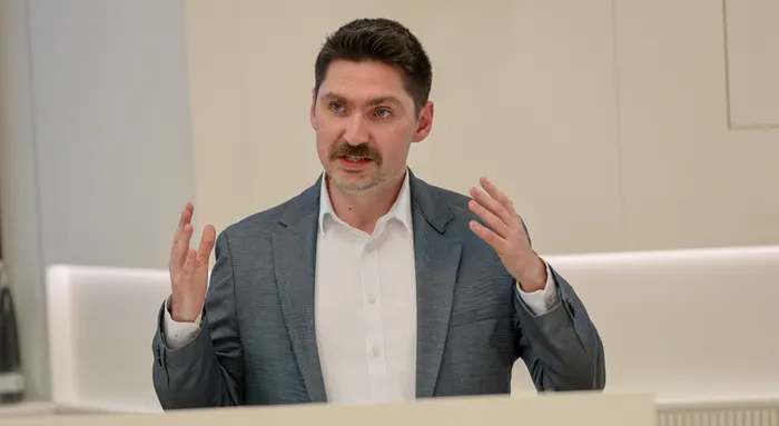 Steffen Wieland, erkennbar an seinem Schnurrbart, gestikuliert während einer Rede oder Präsentation.