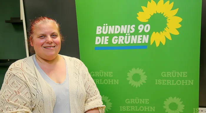 Sylvia Olbrich lächelt in die Kamera. Im Hintergrund ein grüner Banner mit dem Logo von Bündnis 90/Die Grünen und dem Schriftzug 