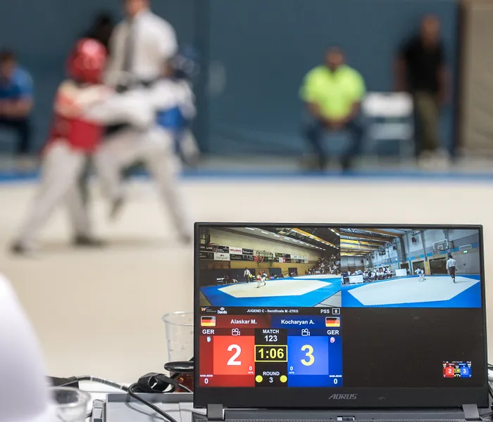 Monitor zeigt Taekwondo-Kampf zwischen Alaskar M. (GER) und Kocharyan A. (GER) mit dem aktuellen Stand von 2:3.