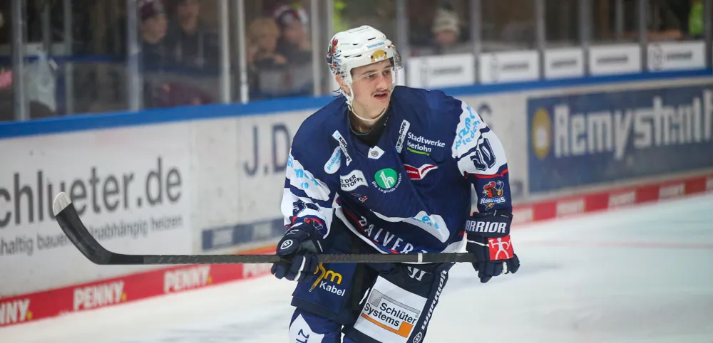 Eishockeyspieler Taro Jentzsch in voller Ausrüstung mit Schläger auf dem Eis, während eines Spiels.