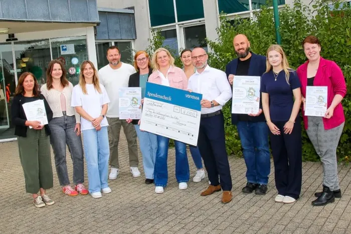 Eine Gruppe von Organisatoren des „Tags der Wohnungslosen“ in Iserlohn hält gemeinsam Spendenchecks, darunter einen Scheck von Vonovia über 4.000 Euro.