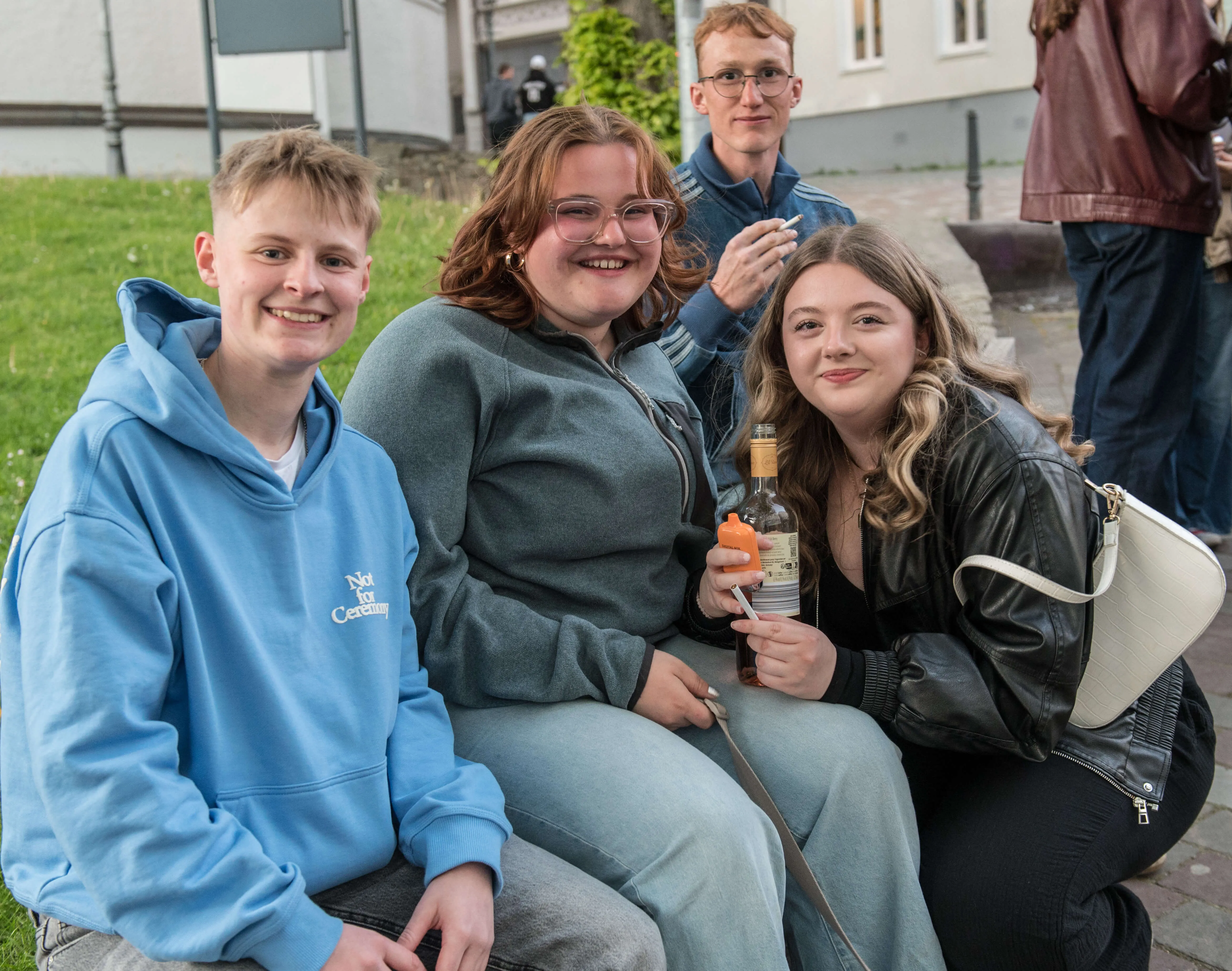 Vier junge Erwachsene sitzen lächelnd eng beieinander, während sie an der Thekentour teilnehmen.