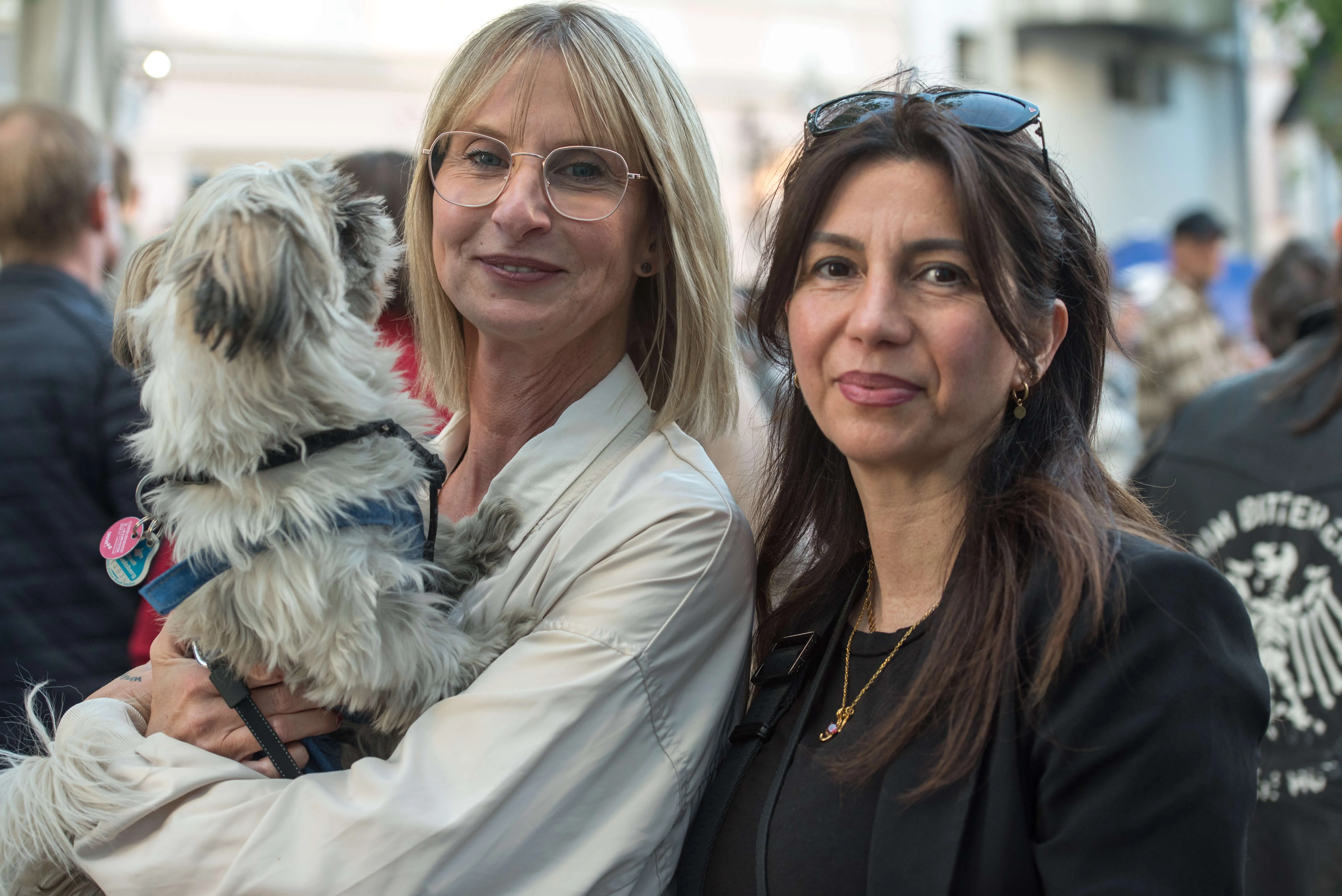 Zwei Frauen mit einem kleinen, zotteligen Hund im Arm stehen vor einer Menschenmenge auf der Thekentour in Lüdenscheid.